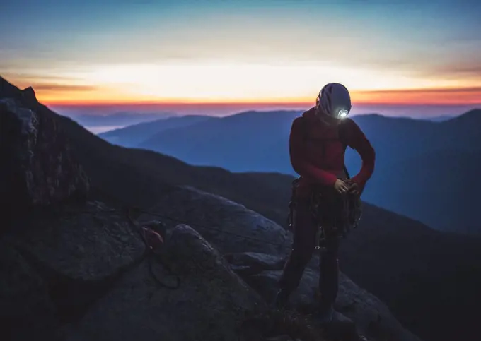 Woman sorting rock gear in the mountains before sunrise