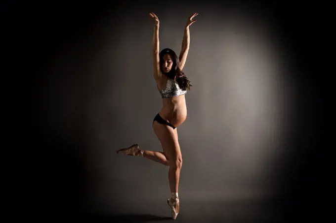 Young pregnant ballerina performing classical ballet pose