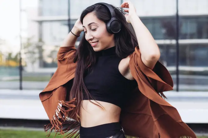 A girl with long hair and headphones dancing on the street