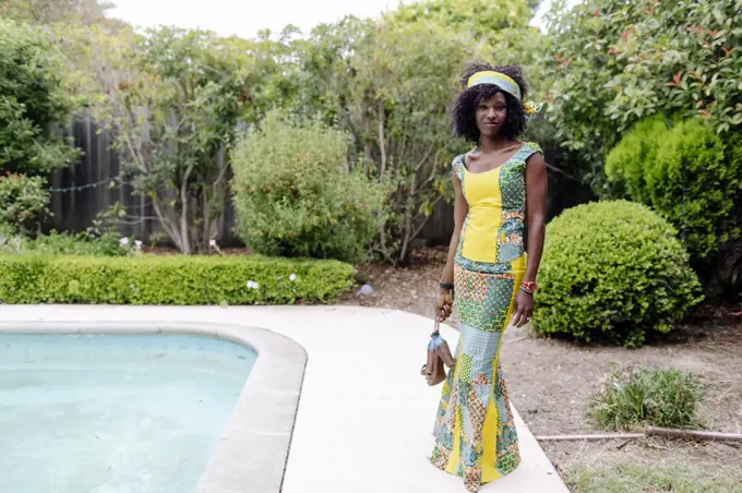 looking camera woman wearing African dress by pool garden