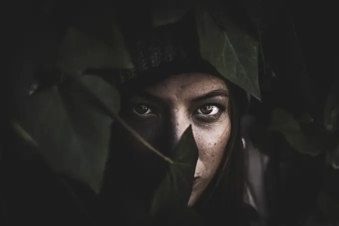 Portrait of a ginger girl with fern leaves covering part her face