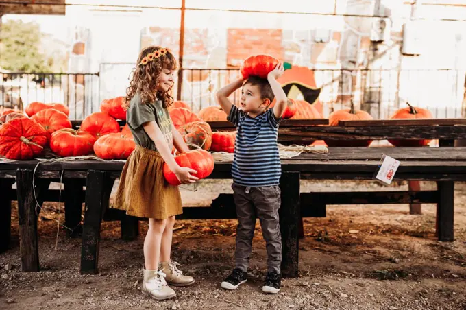 Brother and sister holding cinderella pumpkins at local farmers market