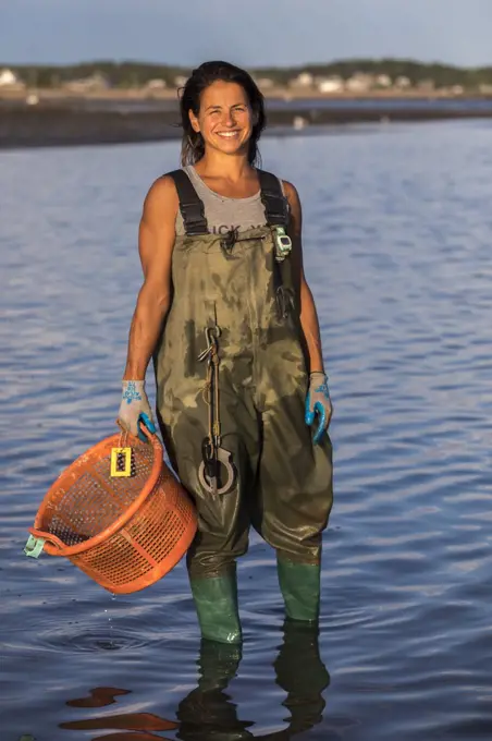 Portrait of female oyster picker in waders smiling at camera