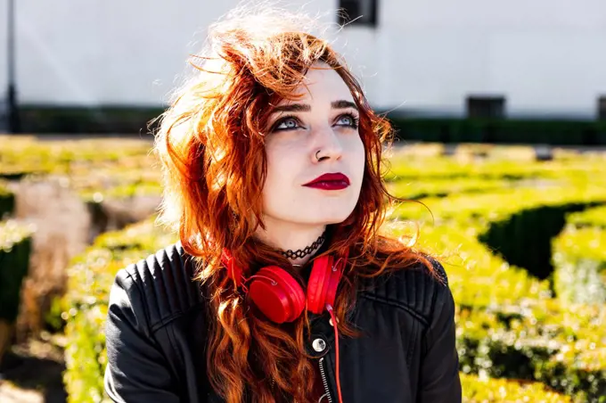 Alternative girl with blue eyes and orange hair relaxing in an urban space.