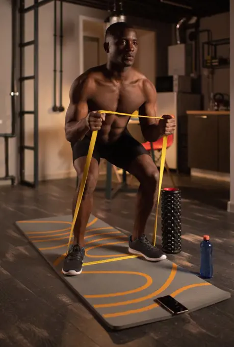 Black sportsman exercising with resistance band online