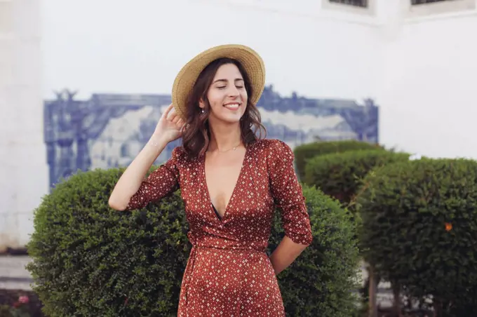 Woman in straw hat and dress smiling with her eyes closed
