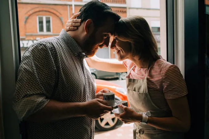 Young couple in love drinking coffee, smiling while standing at door