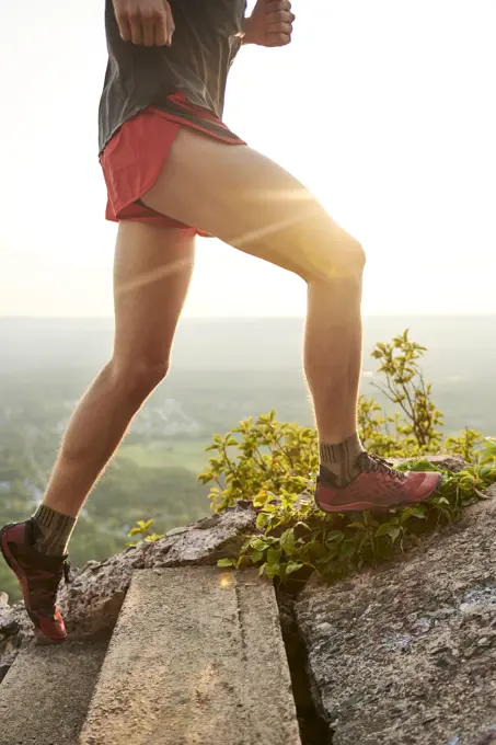 Adult male trail runner on a mountain ridge at golden hour
