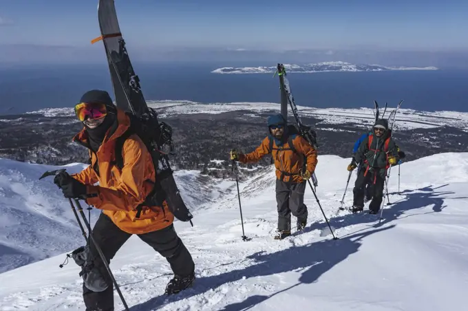 Men with ski poles climbing snowcapped mountain during vacation
