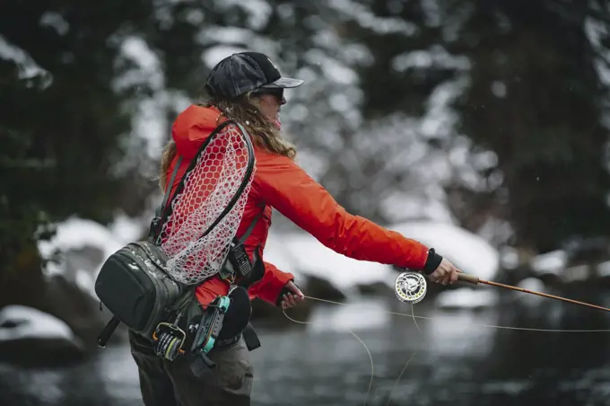 Side view of woman fly fishing during vacation in winter