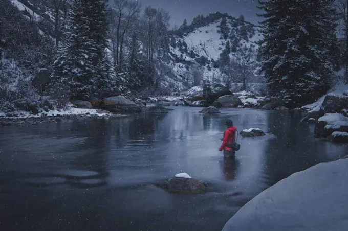 Woman fly fishing in river during snowfall