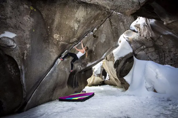 Determined female bouldering in ice caves at Independence Pass