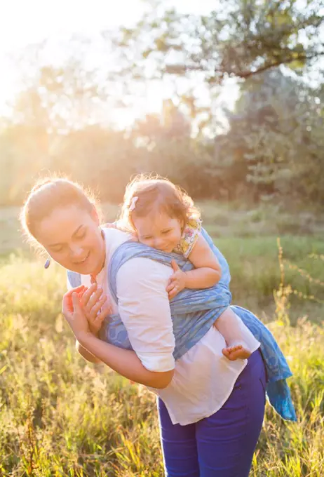 Happy family of mother and wrapped smiling daughter in blue sling back