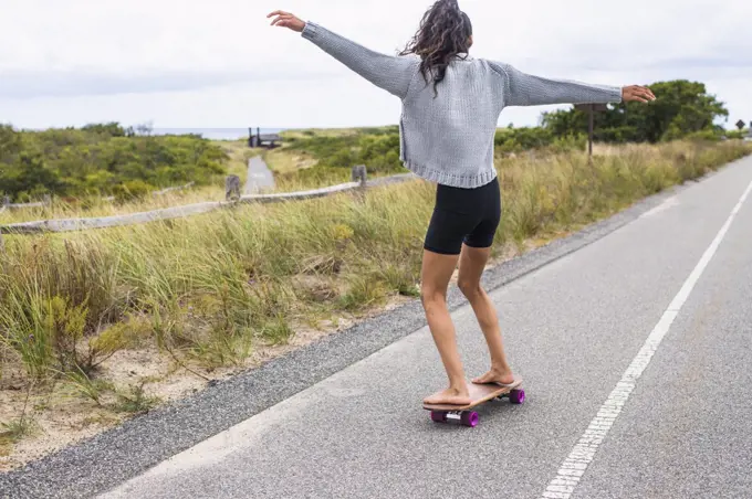 Young Woman skateboarding barefoot on overcast day