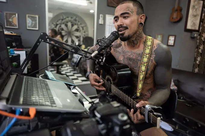 Asian man recording in music studio.