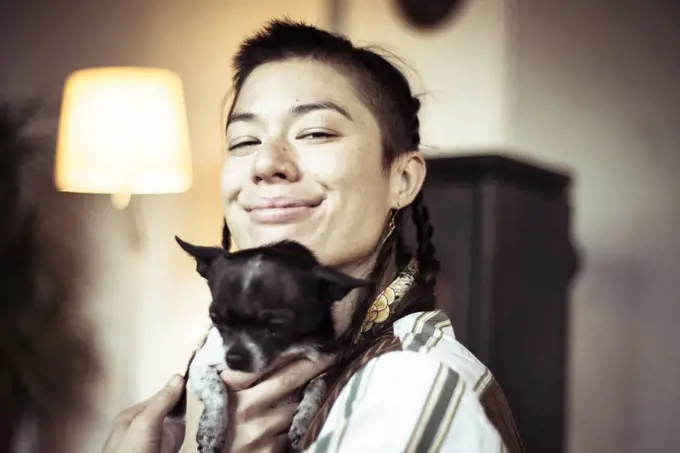 Smiling alternative young queer person with tiny small chihuahua pup