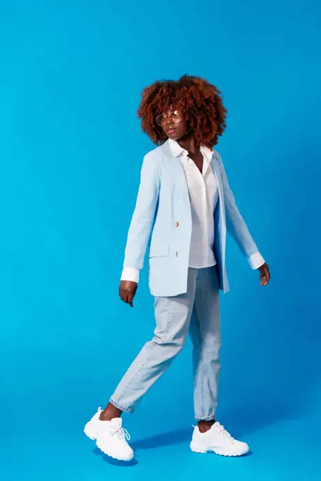 Portrait of fashionable african woman standing on blue background