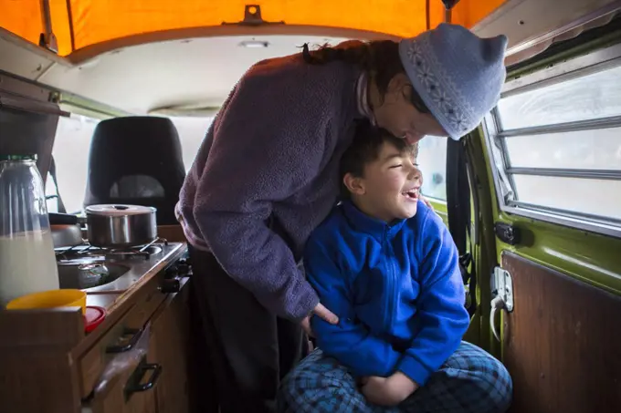 Woman kisses her son on head in VW camper van during family road trip