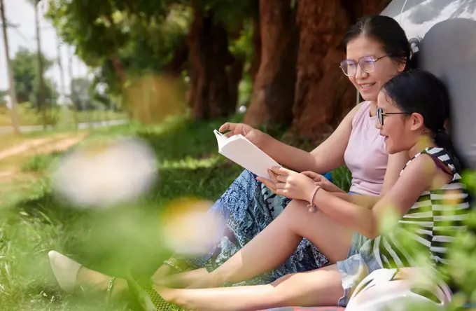 Mother and daughter reading a book in the public park