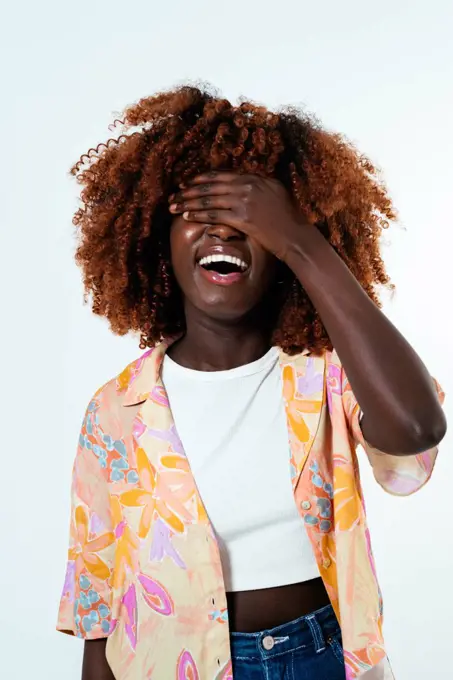 Happy afro woman covering her face over white background