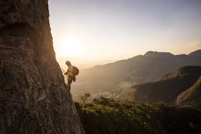 Beautiful view to male climber on steep rocky rainforest mountain
