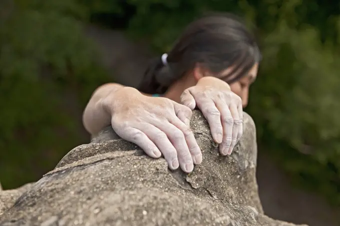 Woman climbing on the sandstone rocks at Harrison's Rock in England