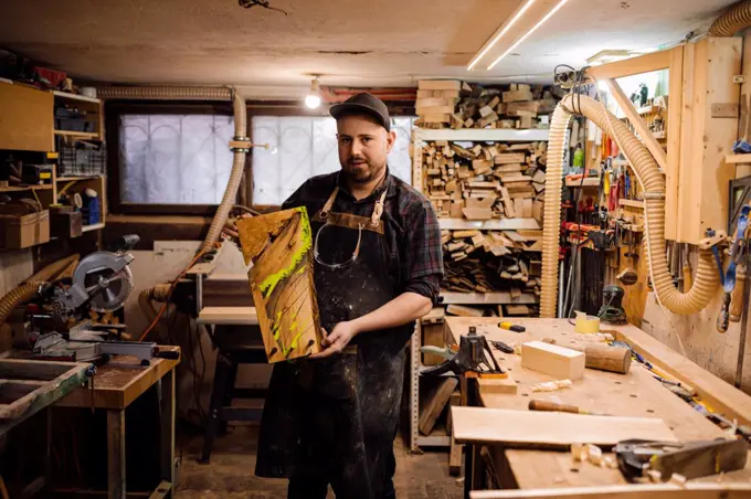 Portrait of carpenter with piece of wood in workshop