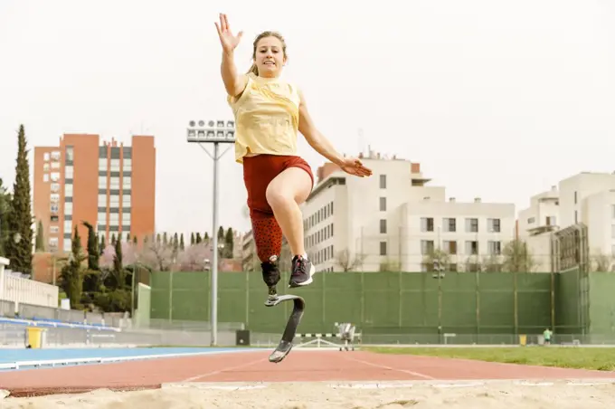 Female athlete with disability running towards sandpit