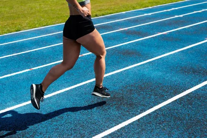 Crop woman athlete running on an athletics track