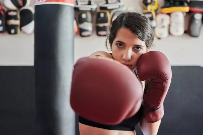 Woman in boxing gloves trains while looking at the camera