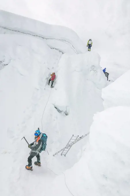 Rope team navigating a big crevasse in the Himalayas