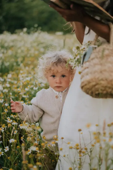A little boy holding on to his mother in a chamomile field