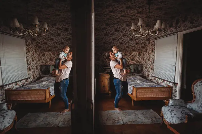 Mom holding baby up in vintage room with mirror reflection
