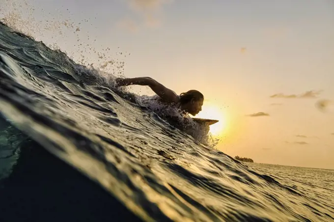 Male surfer in ocean at sunset time