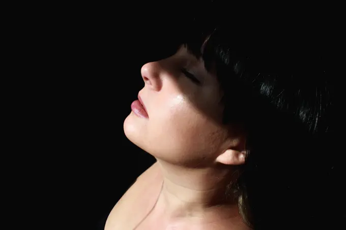 side view of woman's face among lights and shadows, black background