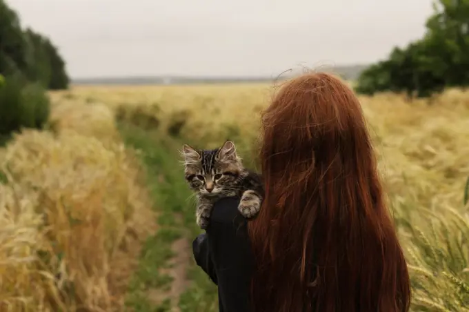 A girl is standing in a field with a cat