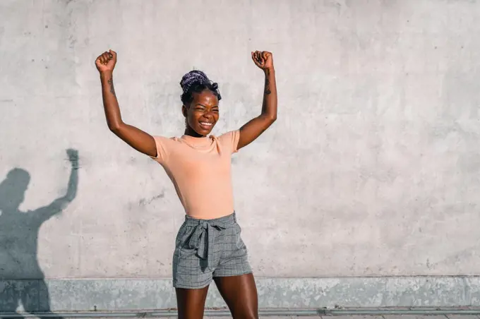 black girl raises her arms in victory sign