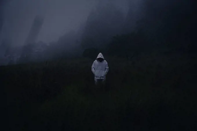 One mysterious man wearing a white hoodie in dark foggy forest