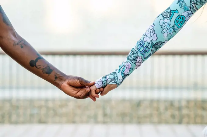 Crop multiracial girlfriends holding hands on street