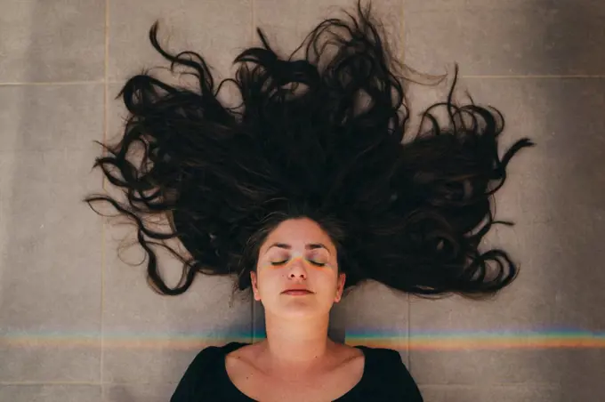 Top view of woman with closed eyes with rainbow prism