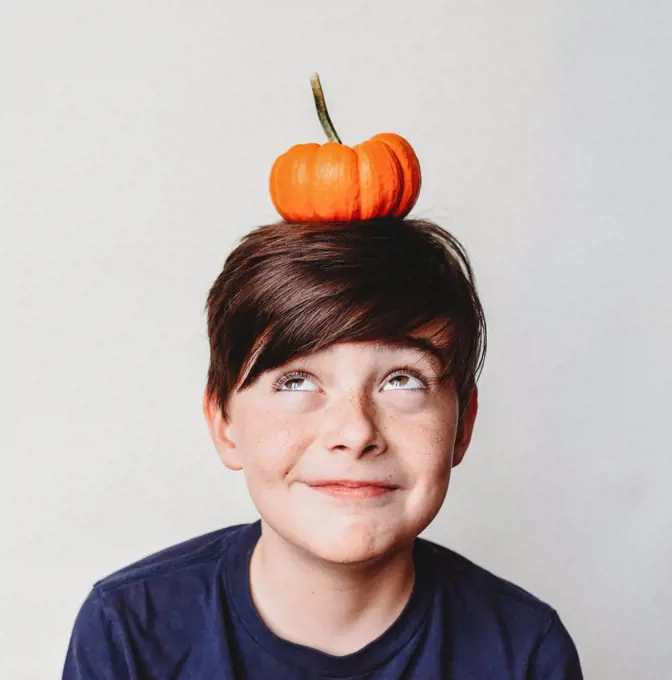 Portrait of happy boy with a small pumpkin on his head.