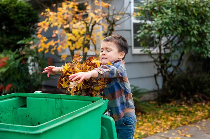 Boy throwing leaves into yard waste bin