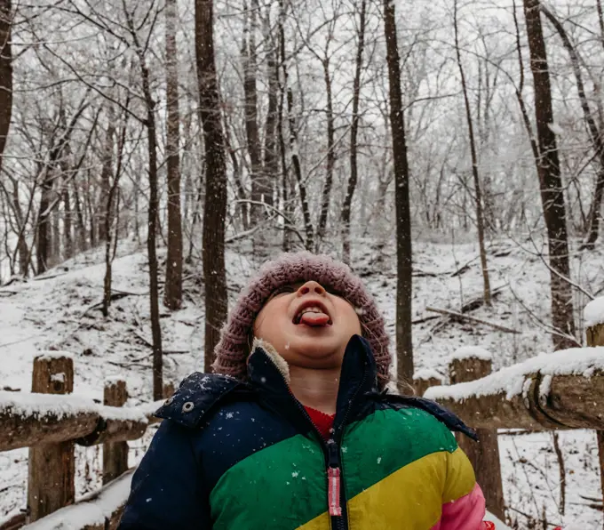 Kid catching snowflakes with tongue in the woods