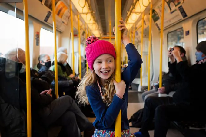 girl happily stood on a train going into London