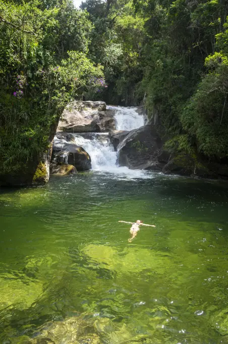 Beautiful view to woman swimming on green pool on rainforest waterfall