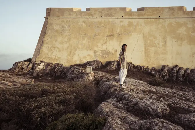 androgynous person stands in front of historic fort in Portugal