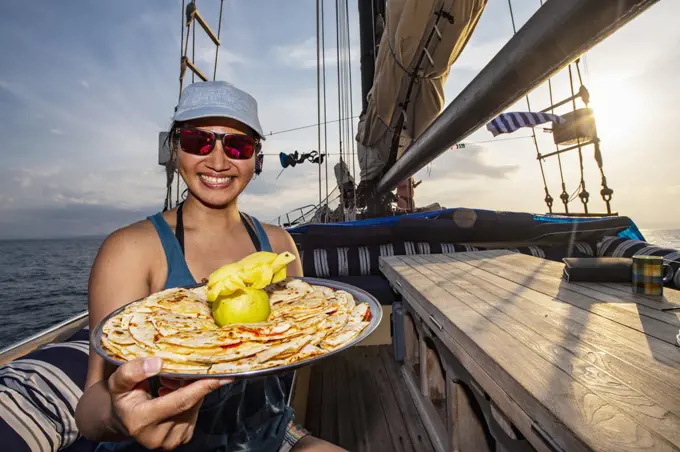 woman on deck of sailboat with a plate of snacks