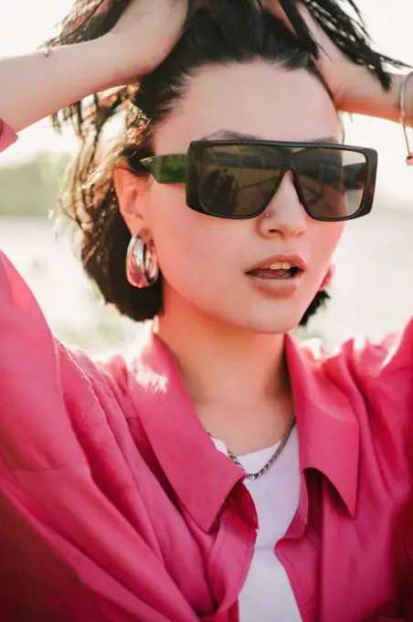 woman dressed in pink shirt wearing sunglasses outdoor in the park