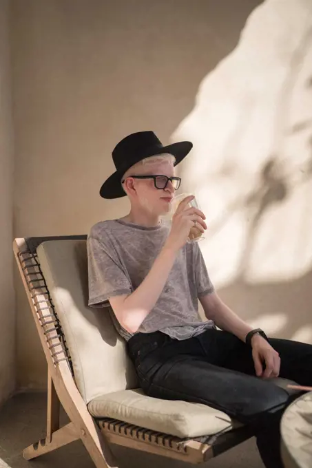 Albino man sitting at the outdoor cafe drinking coffee