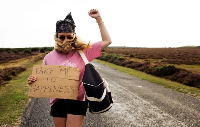 woman protesting with a sign saying take me to happiness